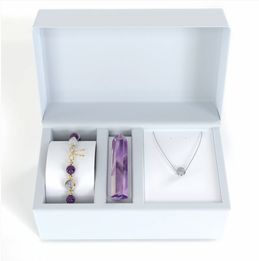 Coffret améthyste composé d'un Bracelet amincissant avec pierres naturelles d'améthyste et de pierre de lune qui alternent avec de petites billes en or fin entre elles, avec une seule pierre de quartz rutile en son centre, entourée d'un anneau en or fin, ainsi qu’un Mehnir en améthyste pure et un collier en argent 925 en fragment de coeur de pierre de lune