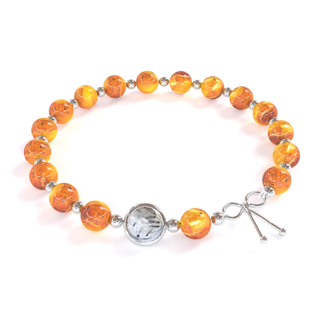 Bracelet apaisant composé de pierre naturelle d'ambre de Birmanie alternant avec de petites billes en or argent, avec une seule pierre de quartz rutile en son centre, ainsi qu'un noeud en argent
