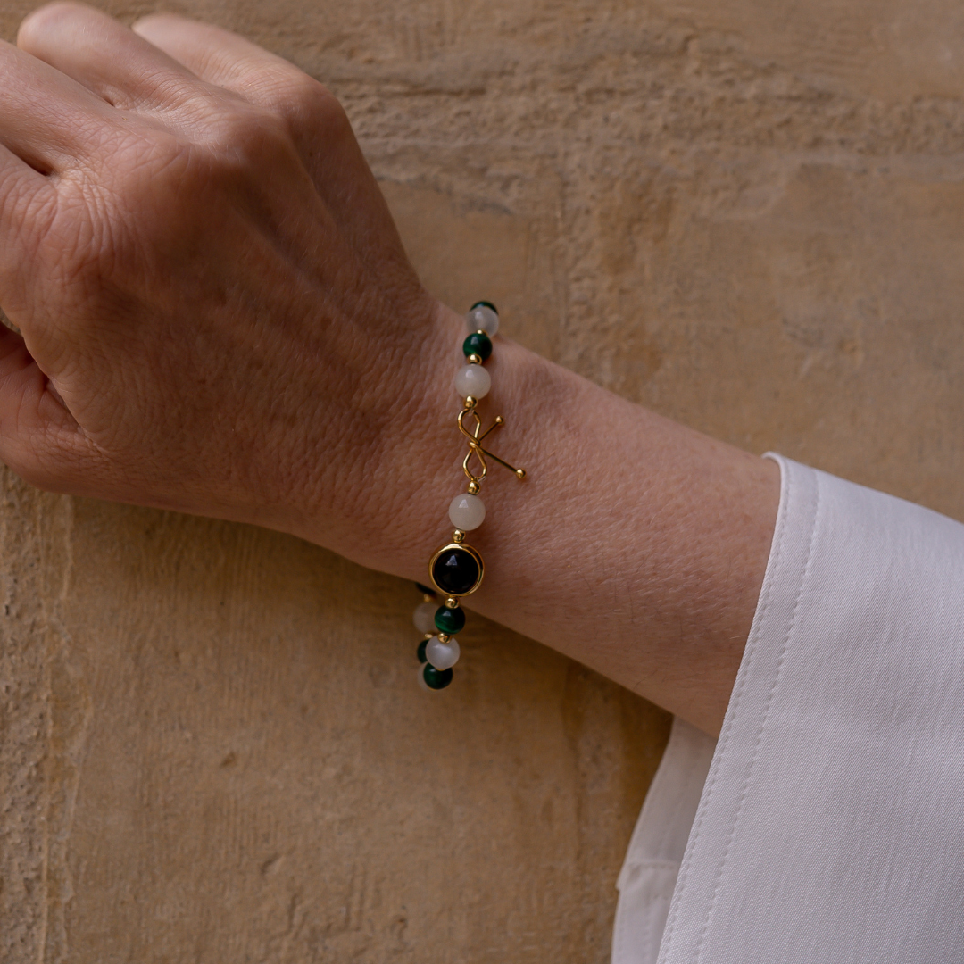 Bracelet anti-douleur composé de malachite et de pierre de lune, alternant avec de petites billes en or fin, avec une seule pierre de quartz rutile en son centre, entourée d'un anneau en or fin.