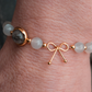 Bracelet anti-ménopause composé de pierre de lune, alternant avec de petites billes en or fin, avec une seule pierre de quartz rutile en son centre, entourée d'un anneau en or fin.