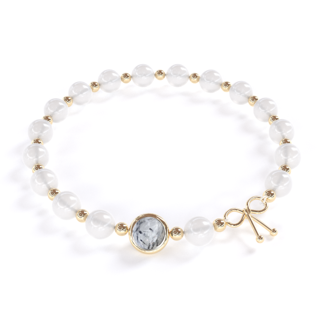 Bracelet anti-ménopause composé de pierre de lune, alternant avec de petites billes en or fin, avec une seule pierre de quartz rutile en son centre, entourée d'un anneau en or fin.